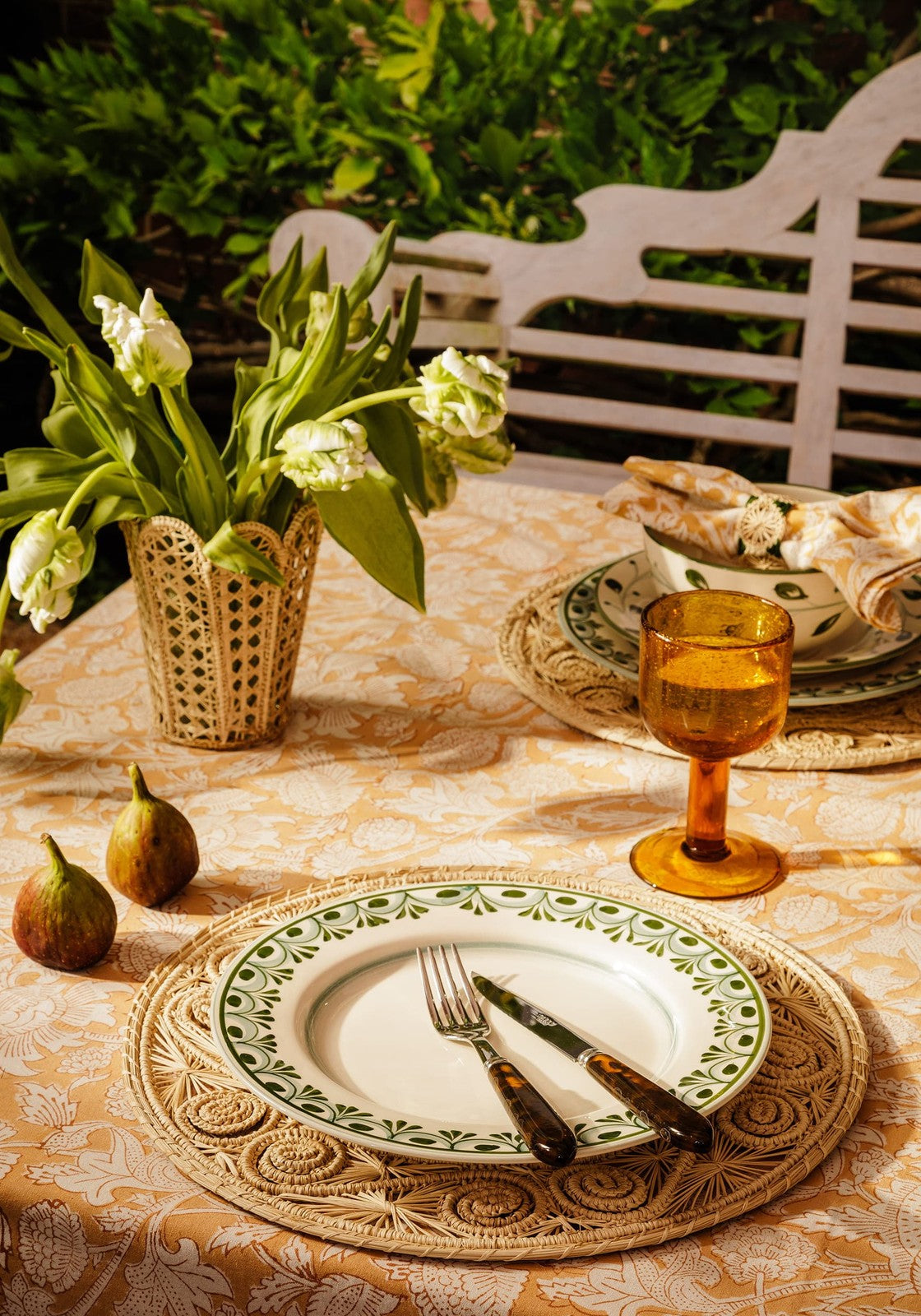 Cordelia dinner plate in white ceramic with a green decorative border on a woven placemat