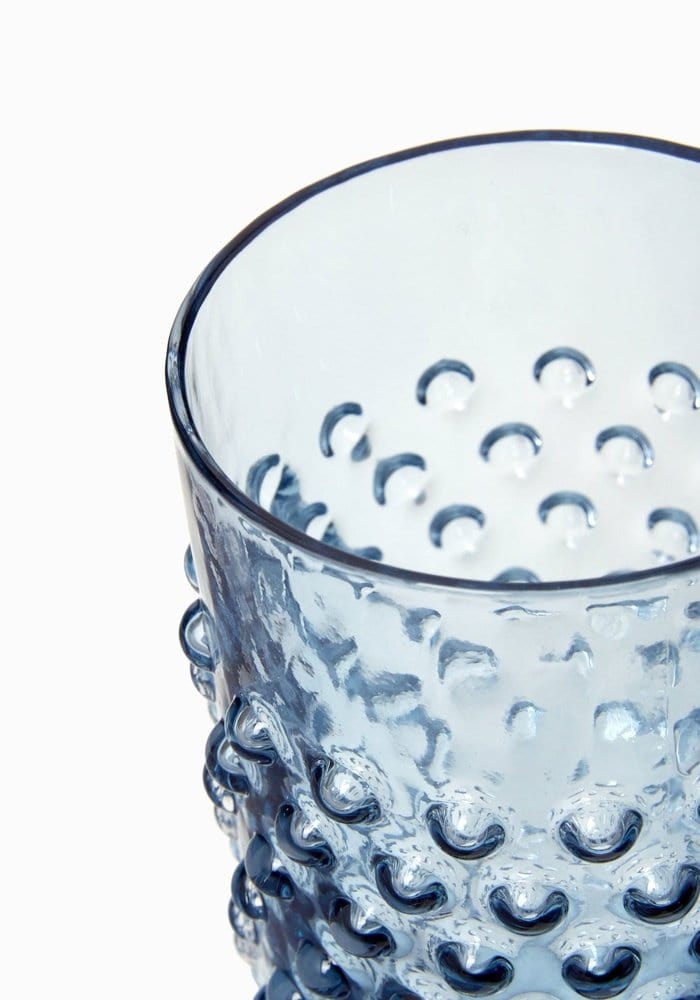 A translucent cornflower blue dew glass tumbler with hobnail texture and smooth rim from a set of 4