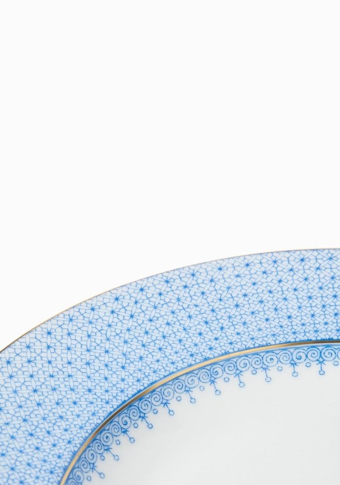 A delicate cornflower blue lace dinner plate set featuring intricate blue and white porcelain with gold trim edges