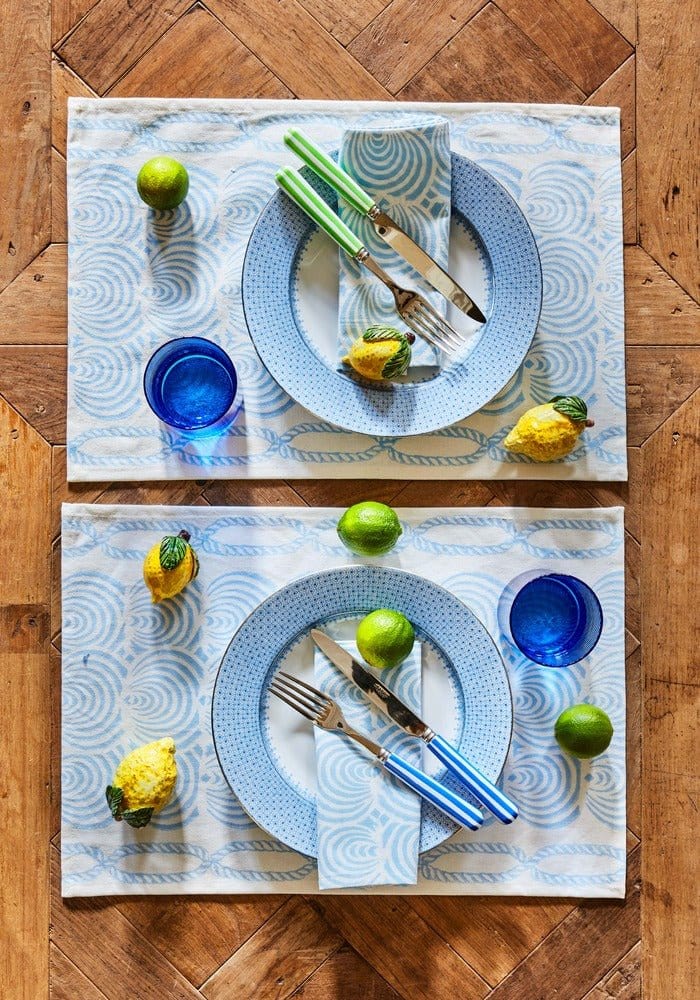 Cornflower blue lace dinner plates set of 4 on a blue lace dinner placemat with swirling design and cutlery on top