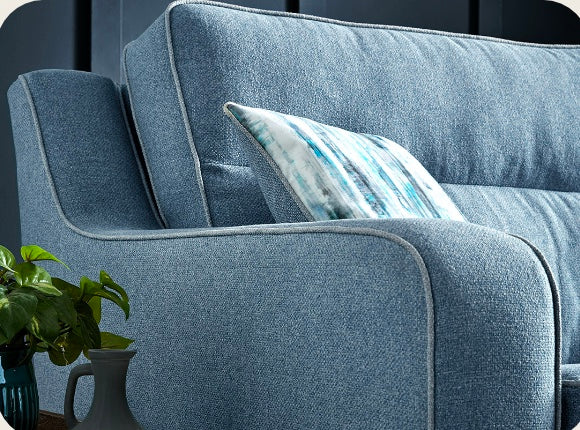 Blue textured fabric cornwall sofa with shaped square arms and a matching cushion with abstract blue and white stripes