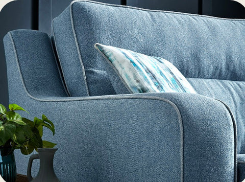 Blue textured fabric cornwall sofa with shaped square arms and a matching cushion with abstract blue and white stripes