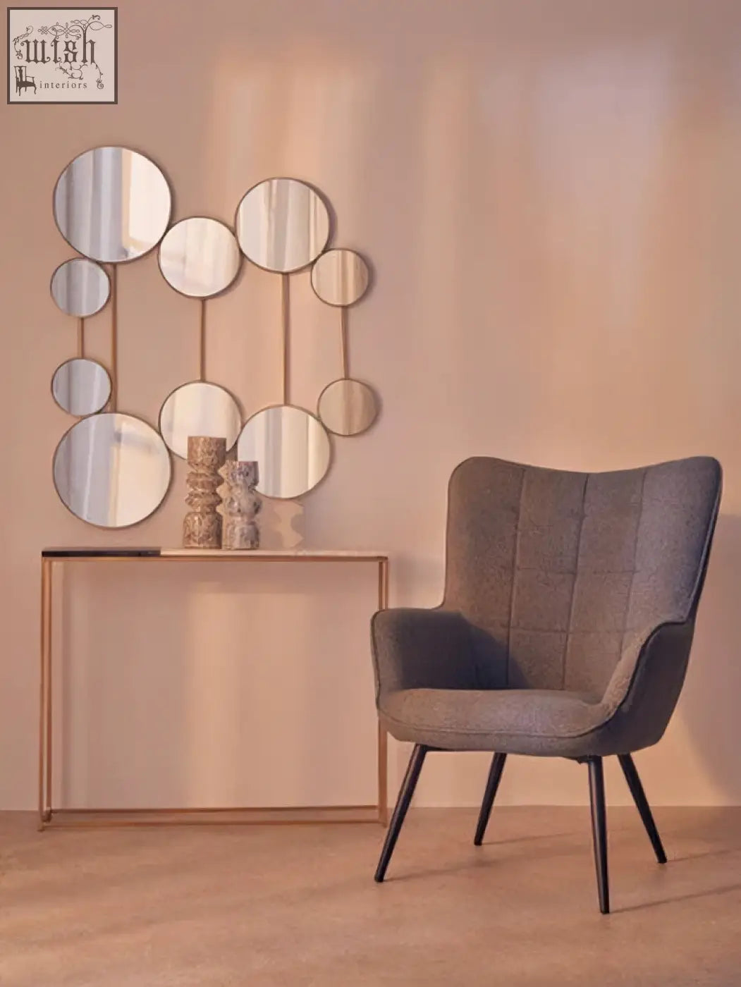 Gray upholstered armchair with tufted back and black metal legs next to corra marble console table with marble console top