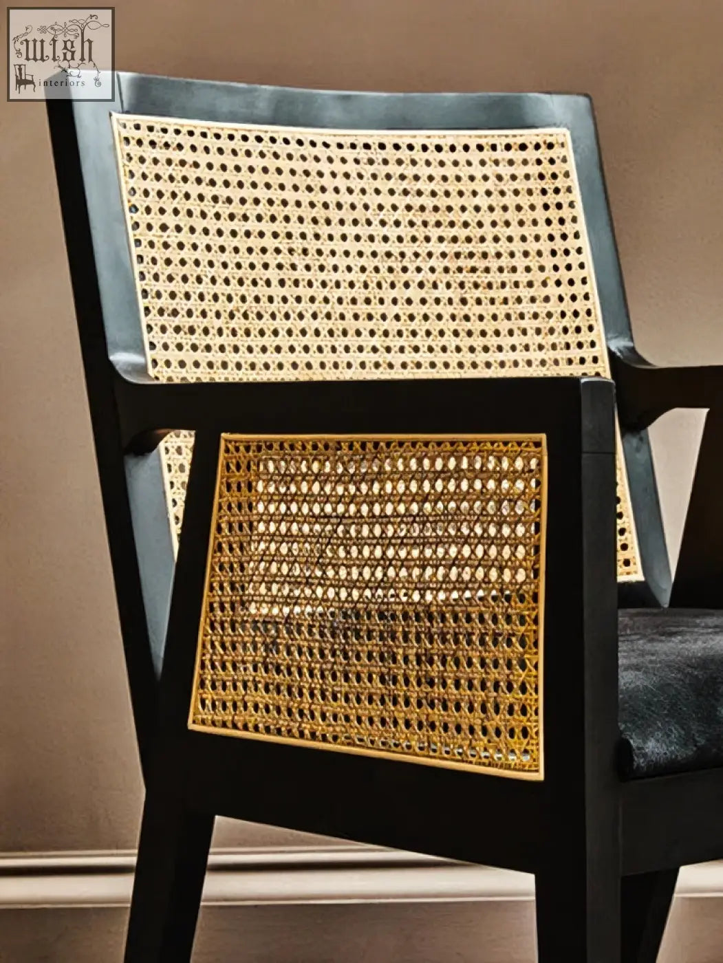Black-framed corso rattan chair with woven cane seat and back and gold-toned accents on the lower panel