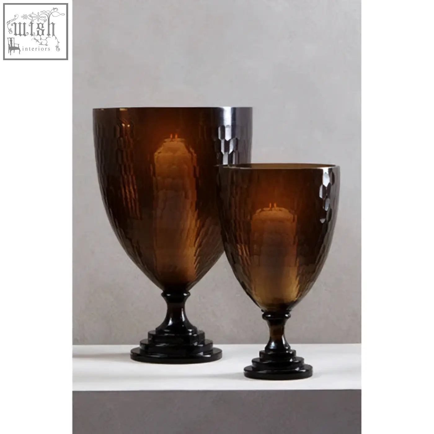 Two amber glass candle holders with textured hammered finish and black bases for cozy candle lighting
