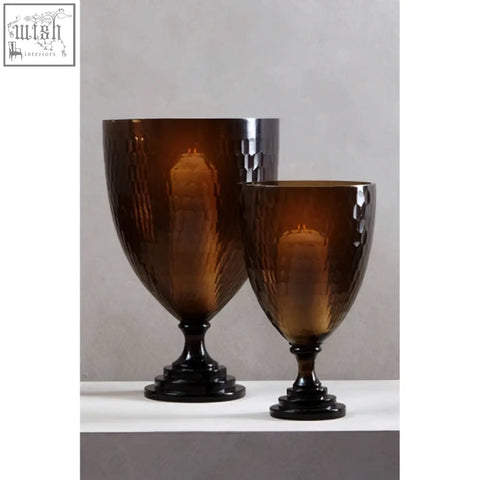 Two amber glass candle holders with textured hammered finish and black bases for cozy candle lighting