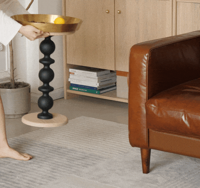 Cosmo round side table featuring a gold tray bowl on a black segmented pedestal with a light wood circular base delightfully blends style