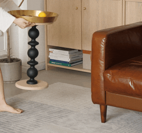Cosmo round side table with gold tray featuring a gold-colored bowl on a black segmented pedestal and light wood base with vintage charm