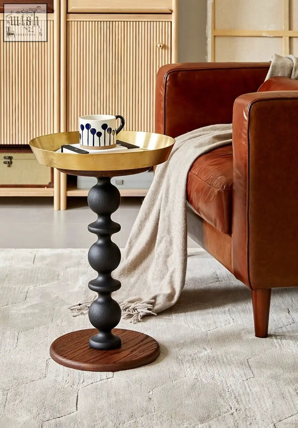 A cosmo round side table with a sleek gold tray top and dark matte pedestal base offers a delightful blend of style