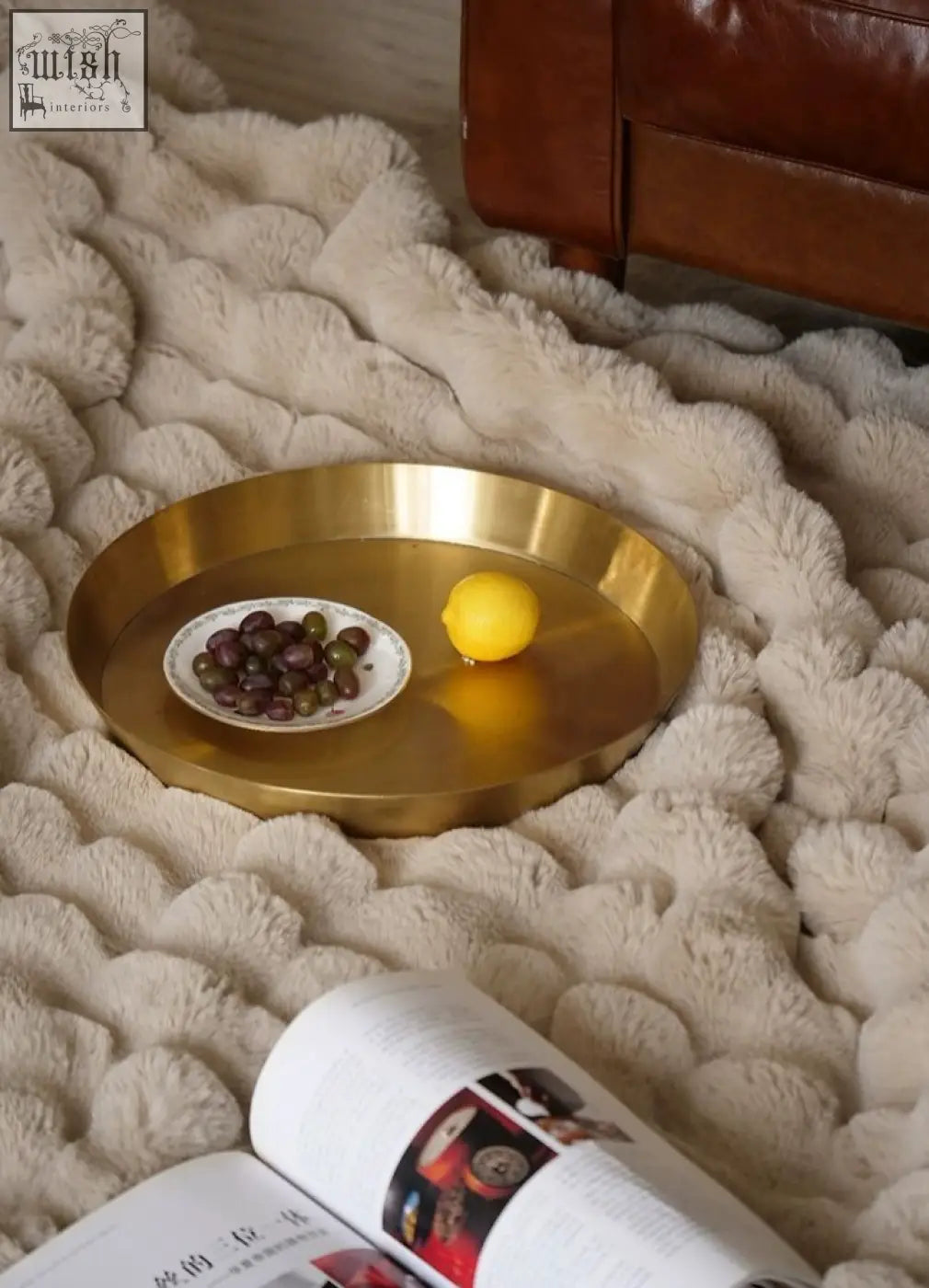 Cosmo round side table with gold tray featuring a smooth reflective surface holding olives and a lemon showcasing vintage charm