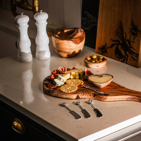 A rustic olive wood cheese board with natural grain patterns paired with country animals butter knives set of 4