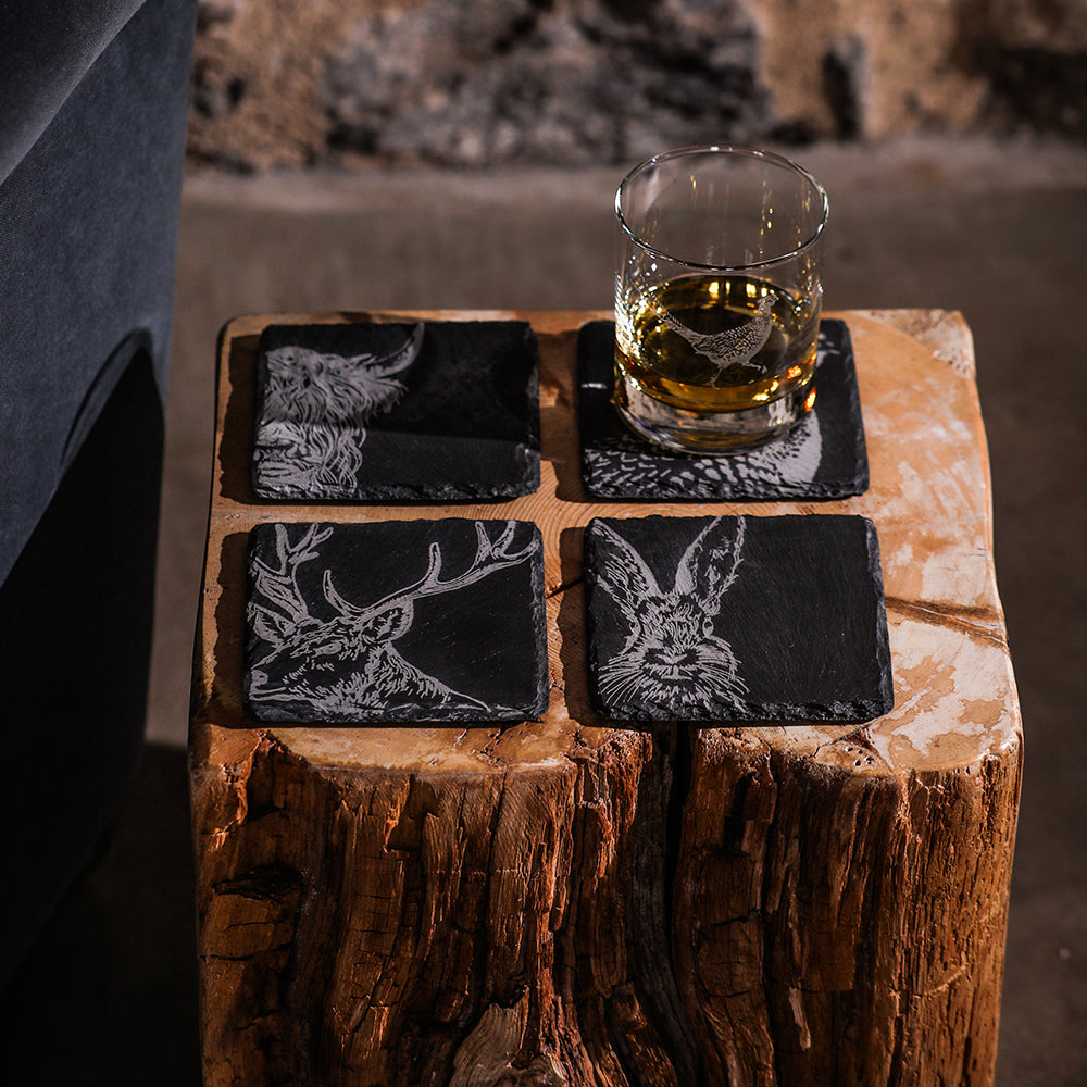 Set of four black slate coasters with white engraved country animals including deer and hare perfect for rustic decor