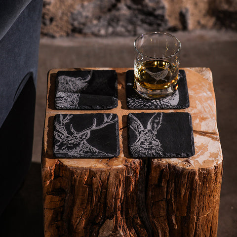 Set of four black slate coasters with white engraved country animals including deer and hare perfect for rustic decor