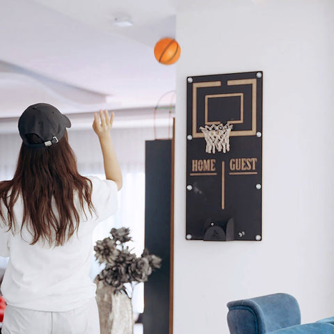 Black wall-mounted basketball wall game with gold trim, white net, home guest text, and target area ball holder on black panel