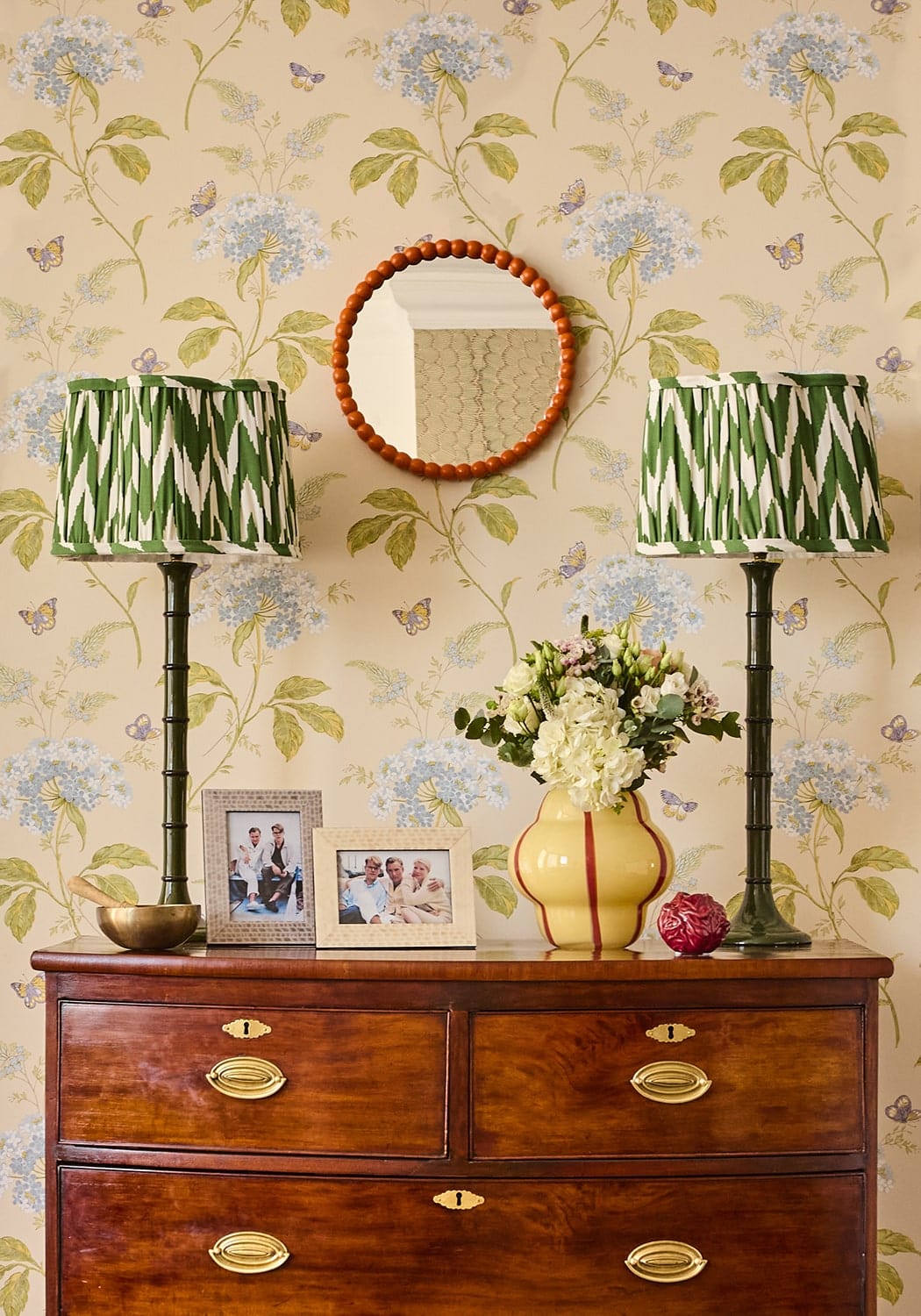 Yellow ceramic vase with red stripes next to cream and beige patterned photo frame 6x4 with floral design