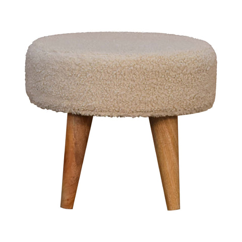 Cream boucle petite footstool featuring a cream-colored plush sheepskin textured round seat with tapered wooden legs