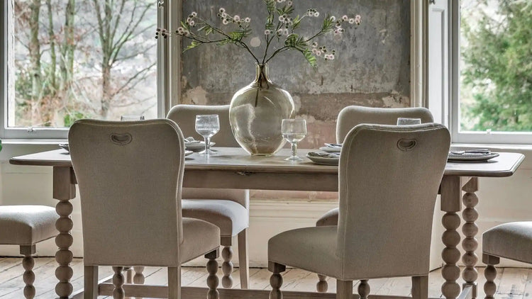 Cream upholstered dining chairs with wooden spindles and turned legs.
