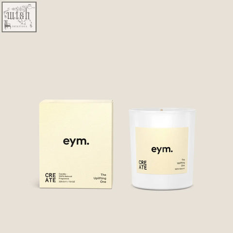 White glass standard candle with pale yellow eym label the uplifting one and matching cream-colored box