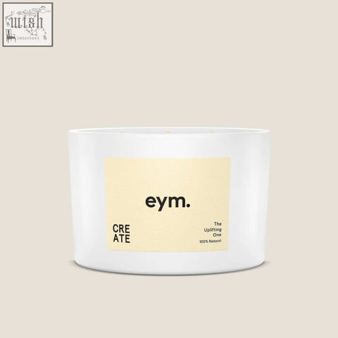 A white cylindrical three wick candle from eym with a pale yellow label called the uplifting one 100% natural