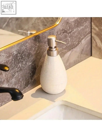 Cream-colored retro style ceramic soap dispenser with brushed metal pump for hand soap in bathrooms kitchens and toilets