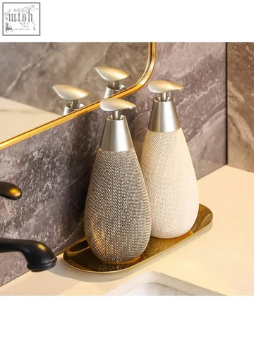 Two elegant retro style ceramic soap dispensers in textured silver and smooth cream with metallic pumps for hand soap use