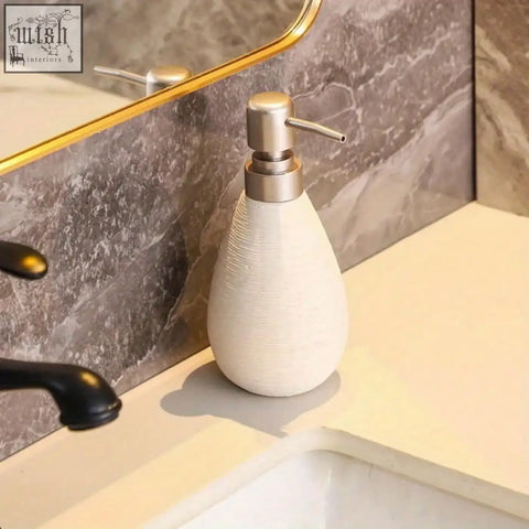 Cream-colored retro style ceramic soap dispenser with brushed metallic pump for hand soap in bathrooms and kitchens