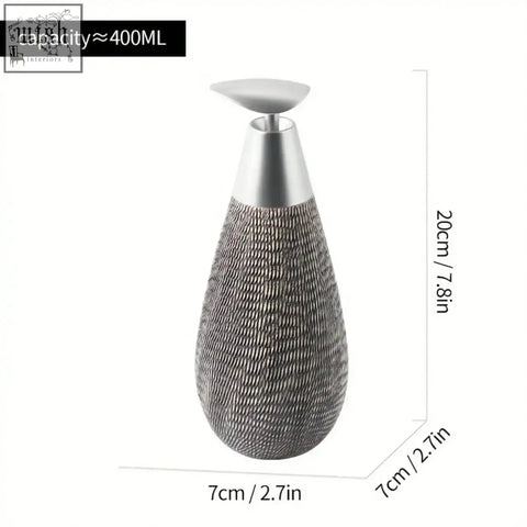 Silver-toned textured ceramic soap dispenser with a sleek metallic pump top perfect for retro style hand soap use