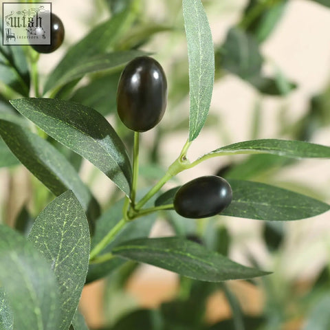 Black glossy artificial olives on a branch with vibrant green leaves on the artificial olive tree for indoor decor