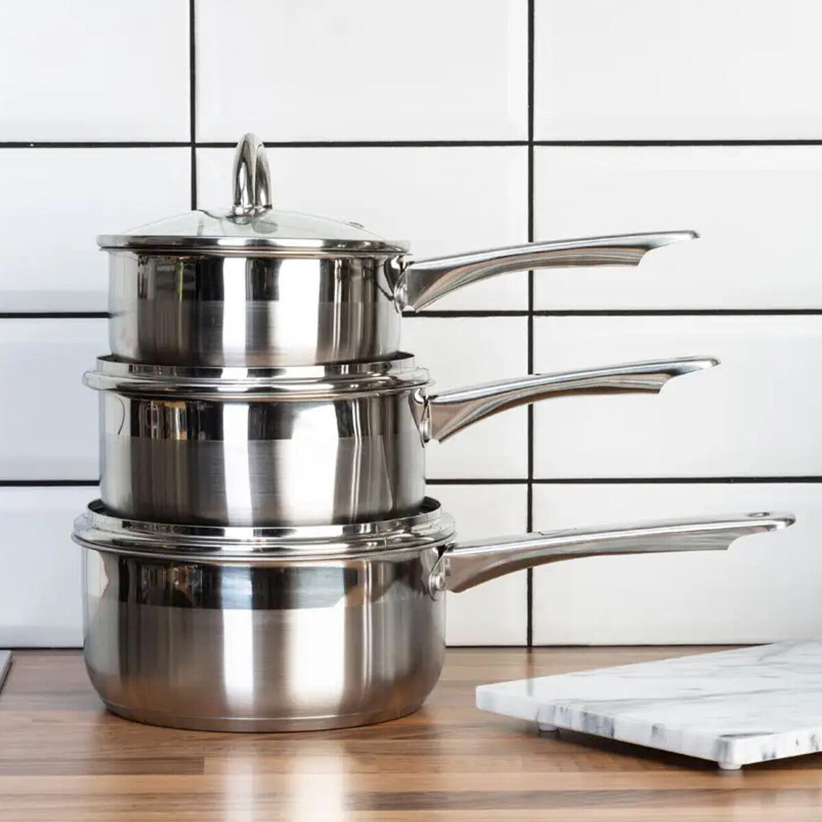 Stacked crosse set of 3 stainless steel saucepans with lids featuring sleek handles and polished metallic finish