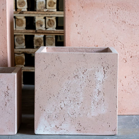 A blushstone 20cm square concrete planter with matte pink textured surface and chipped edges perfect for compact greenery on garden tables