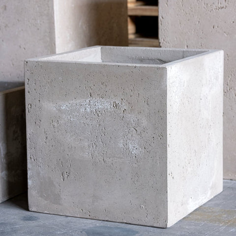 Gray pigmented concrete cube planter with rough texture and chipped edges perfect for kitchen counters plant displays