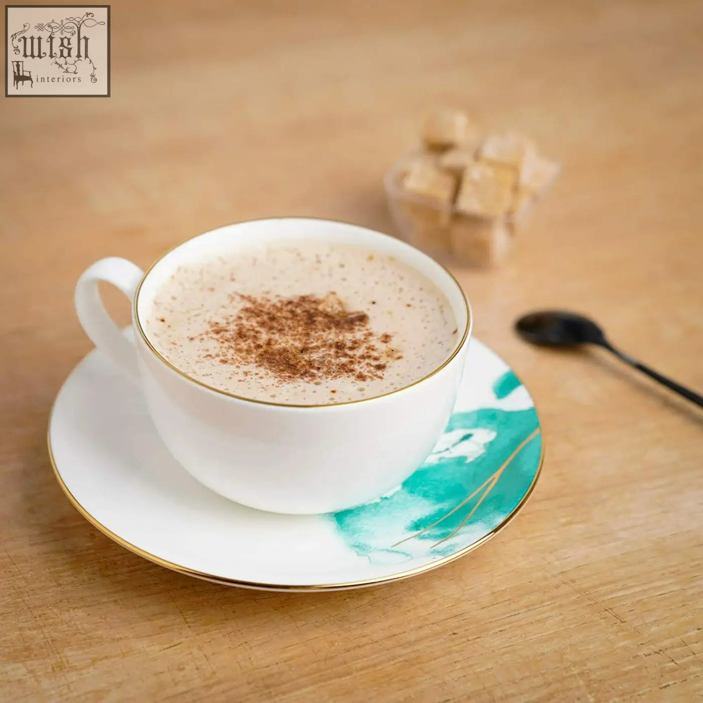 White ceramic coffee cup with gold banding filled with cinnamon dusted latte made from premium porcelain bone china
