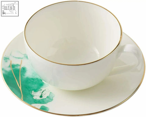 White porcelain teacup with gold banding and green watercolor design on a matching premium porcelain saucer