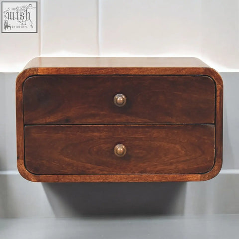 A dark brown california walnut finish wall-mounted bedside table with two drawers and round brass knobs