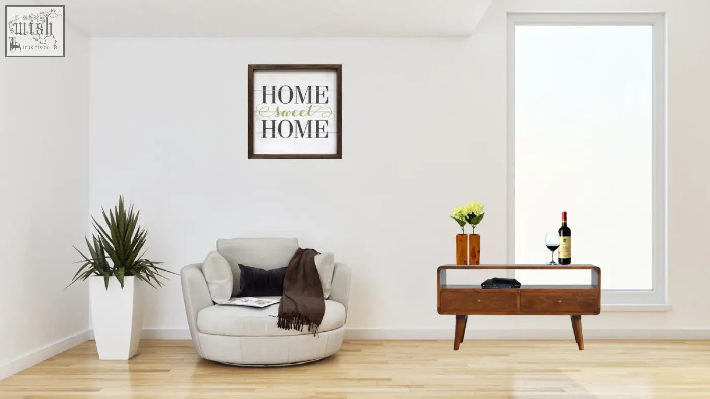 A framed home sweet home wall art in elegant script with a dark brown frame on a curved chestnut mango wood chest of drawers
