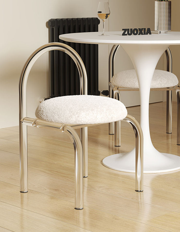 A modern curved clear plastic dressing table chair with a sleek chrome frame and plush cashmere seat pad