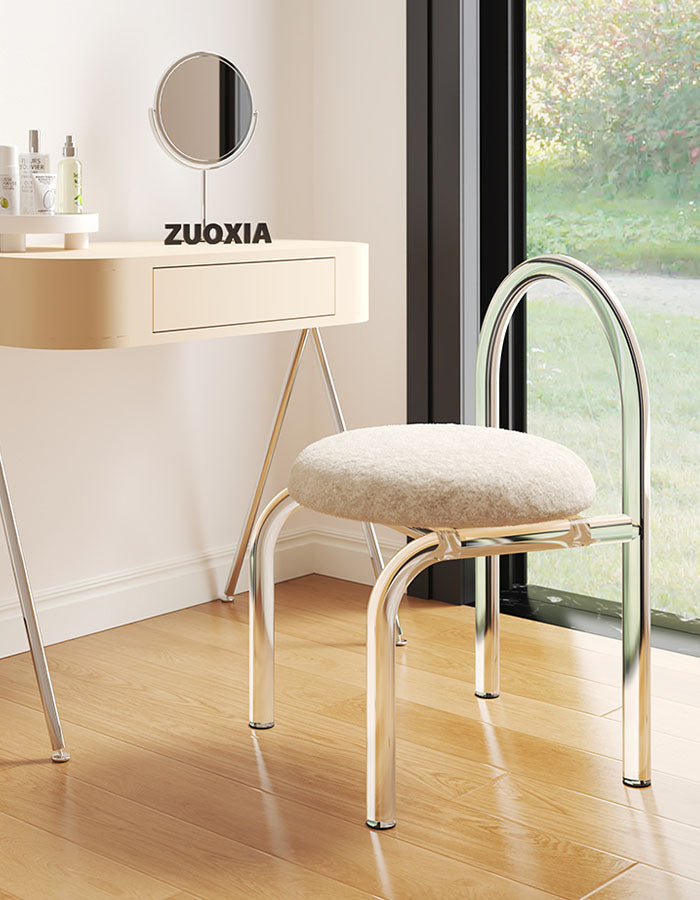 A sleek curved clear plastic dressing table chair with chrome frame and plush cashmere seat pad in off-white