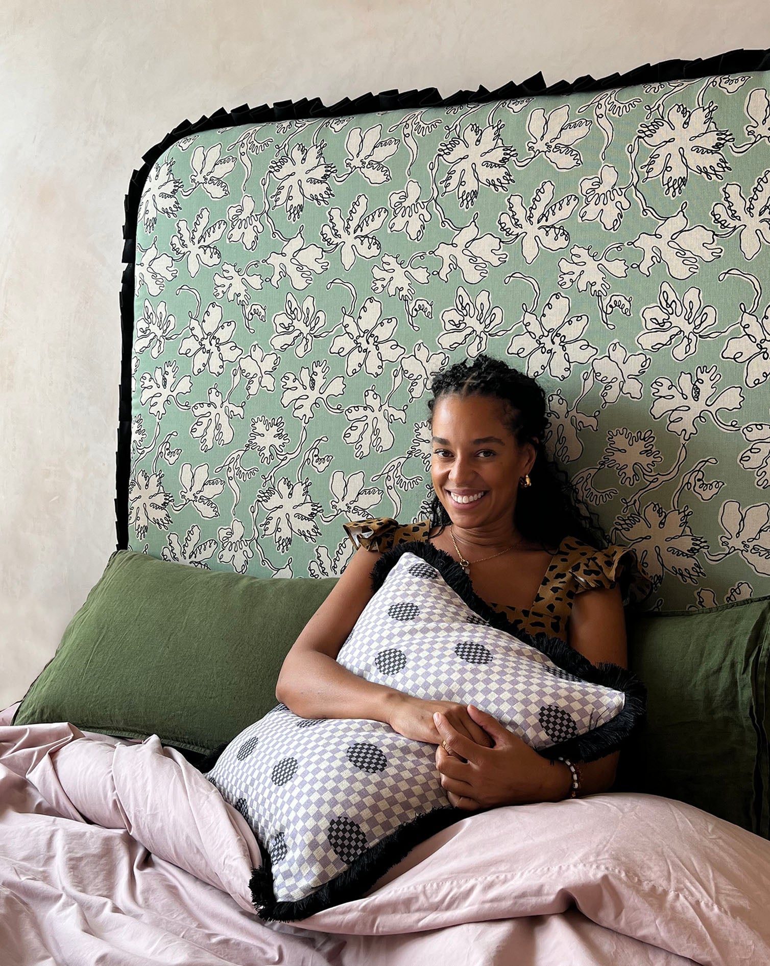 A black-and-white checkered plush pillow with dark polka dots and black fringe from micaela sharp curved frill natural linen collection