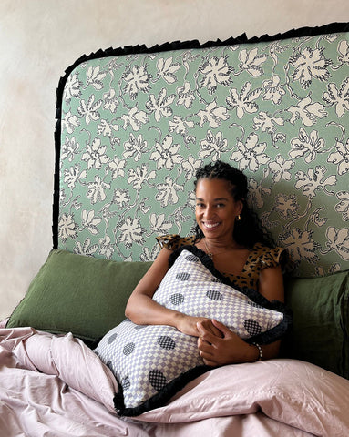 A black-and-white checkered plush pillow with dark polka dots and black fringe from micaela sharp curved frill natural linen collection