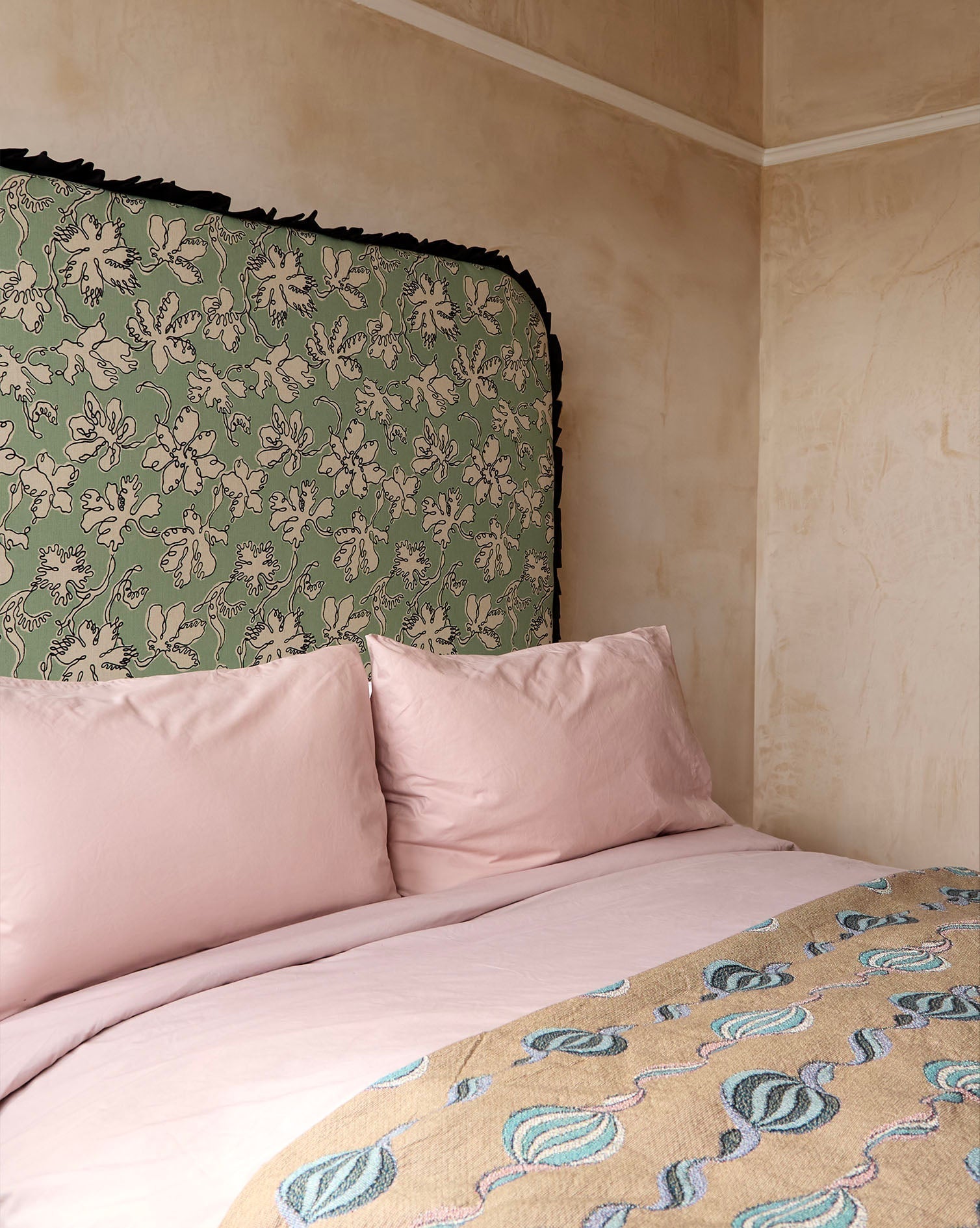 Curved frill headboard in seafoam natural linen with green floral pattern and black fringed edge by micaela sharp