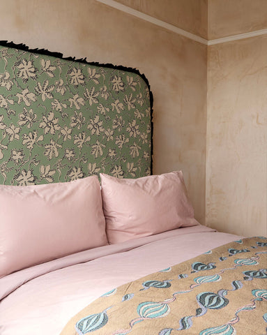 Curved frill headboard in seafoam natural linen with green floral pattern and black fringed edge by micaela sharp