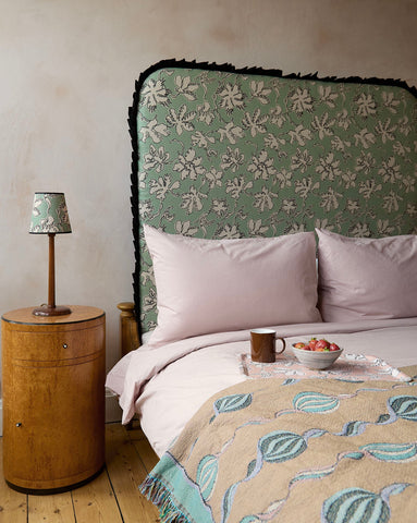 A sage green sage green curved frill headboard with white floral pattern and black fringe in natural linen by micaela sharp
