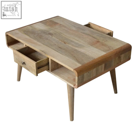 A curved oak coffee table with a light wood top, two side drawers, and tapered legs made from solid mango wood