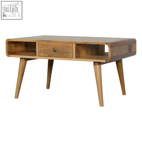 Curved oak coffee table with light solid mango wood finish, tapered legs, and integrated drawer for storage