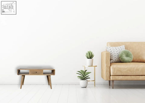 Tan leather sofa with geometric pillow and round green cushion next to a curved oak solid mango wood coffee table