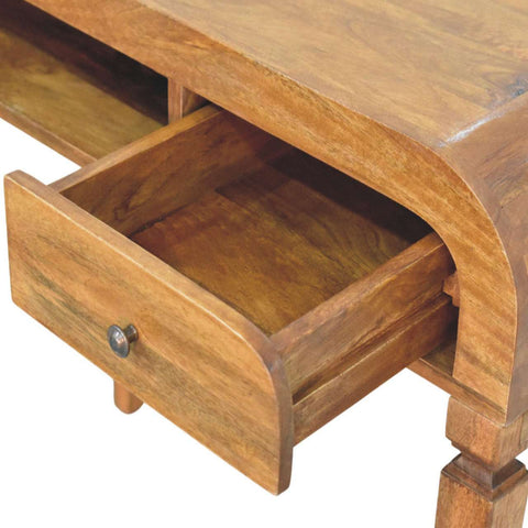 A warm-toned wooden curved open shelf writing desk with a curved drawer front and metallic knob