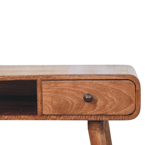 A warm-toned wooden curved writing desk with a single drawer and round dark metal knob