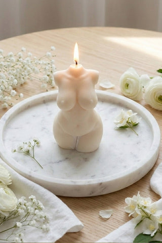 A creamy beige curvy body candle shaped like a female torso with smooth wax and a lit wick perfect for decor