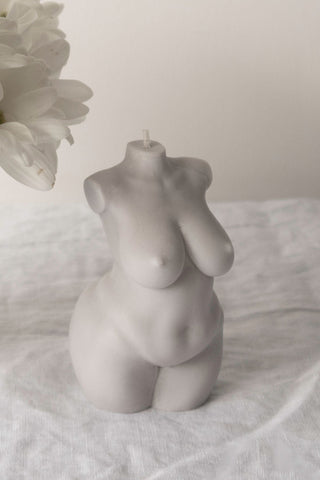 Curvy body candle in smooth matte gray shaped like a stylized female torso with rounded curves and a central wick