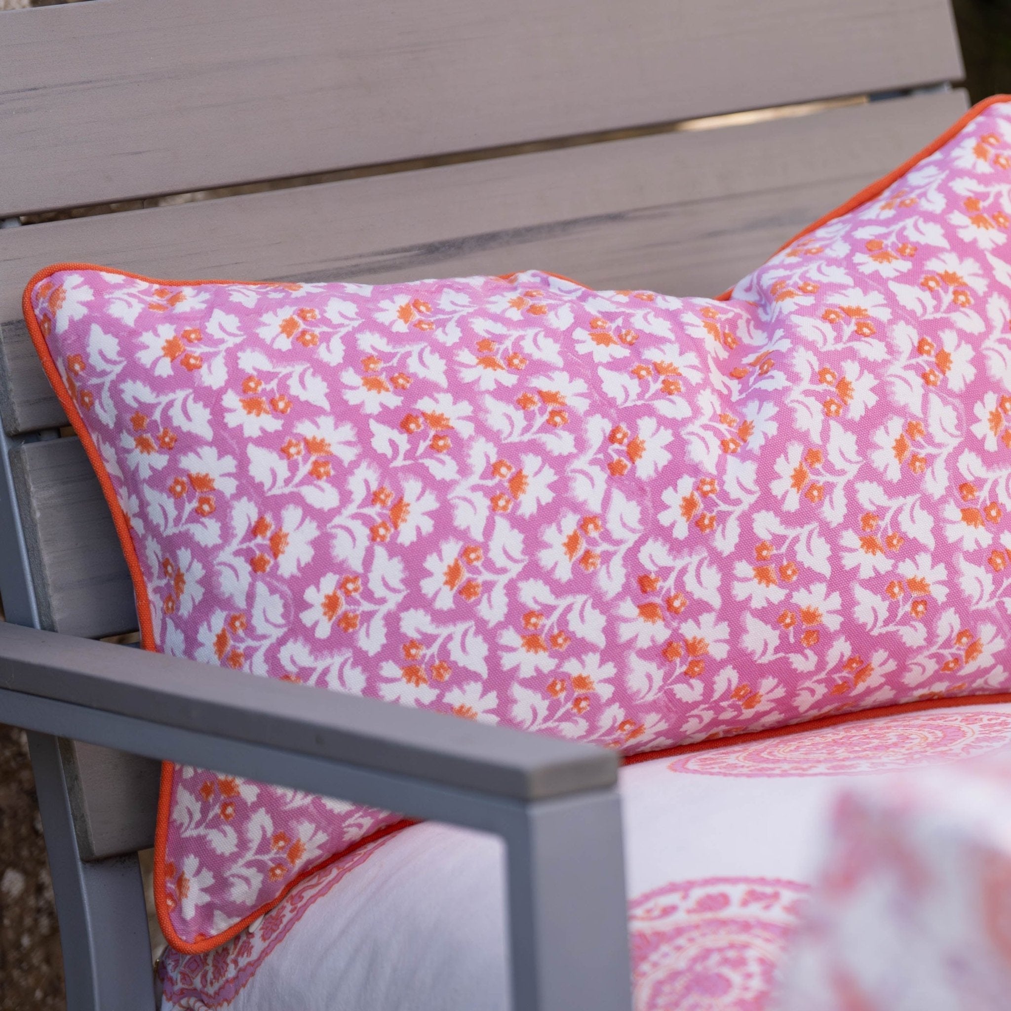 Pink burnt spice cushion cover with hand block white and orange floral pattern and orange trim